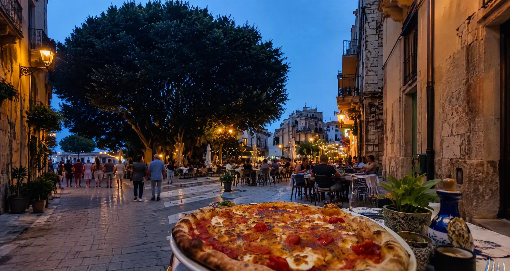Una via del centro di Castellammare del Golfo al tramonto, con la pizza in primo piano
